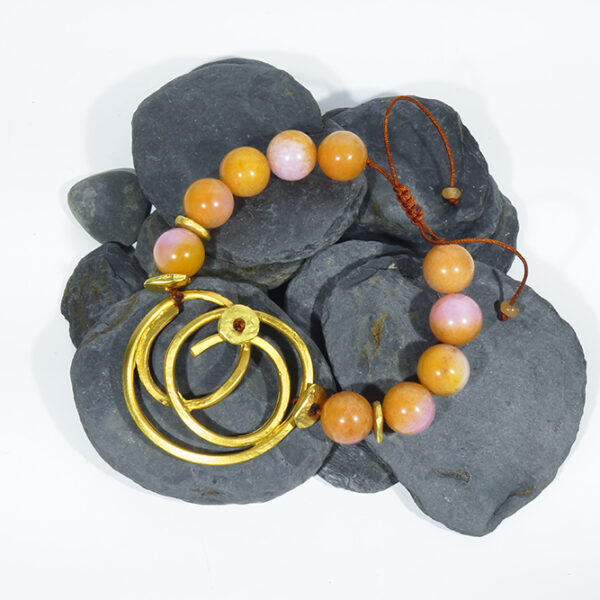 Pulsera artesanal con nudo en dorado mate y jades tallados en naranja y rosas.
